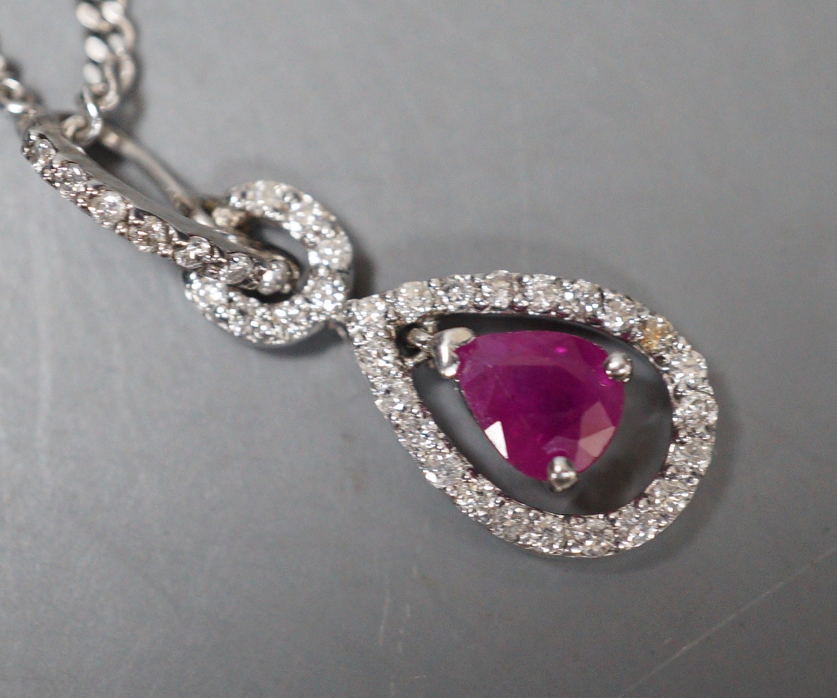 A modern white metal, ruby and diamond chip set pear shaped drop pendant, 20mm, on a 9ct white gold chain, 44cm, gross weight 5.3 grams.